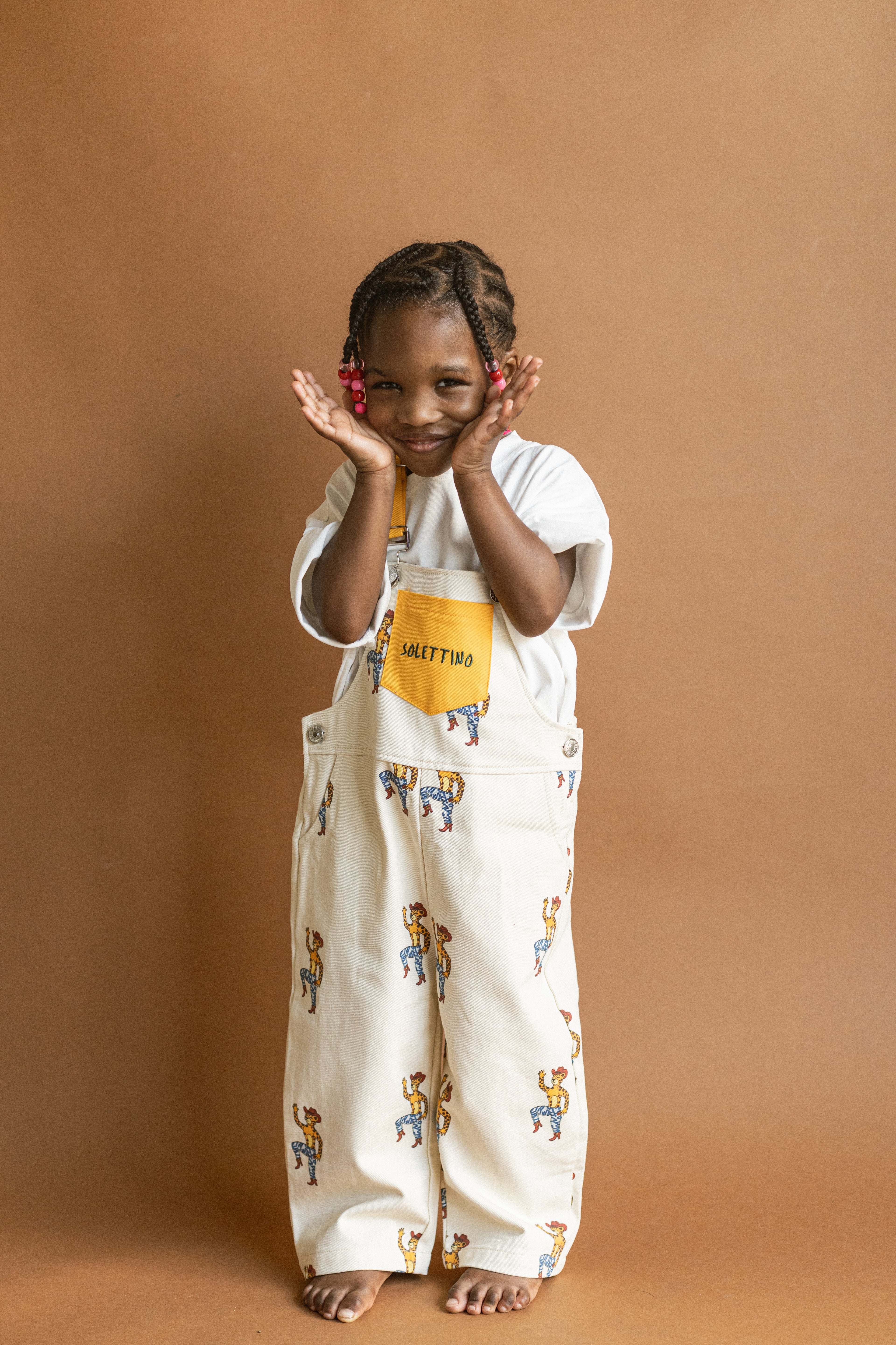 Child wearing a white outfit with colorful patterns on a brown background