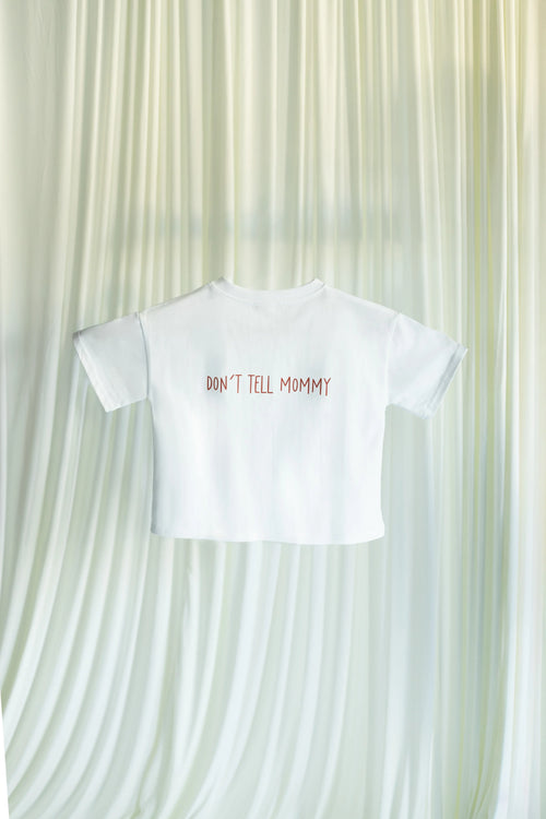 White t-shirt with 'DON'T TELL MOMMY' text on a textured white background