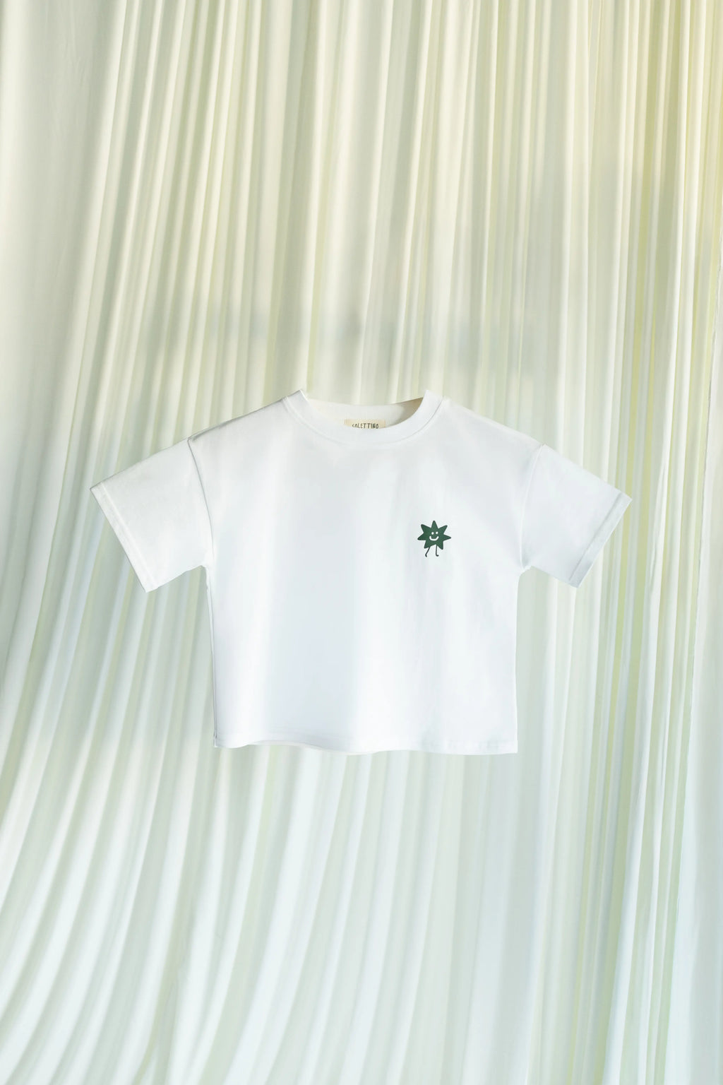 White t-shirt with Solettino Kids green logo on a white background