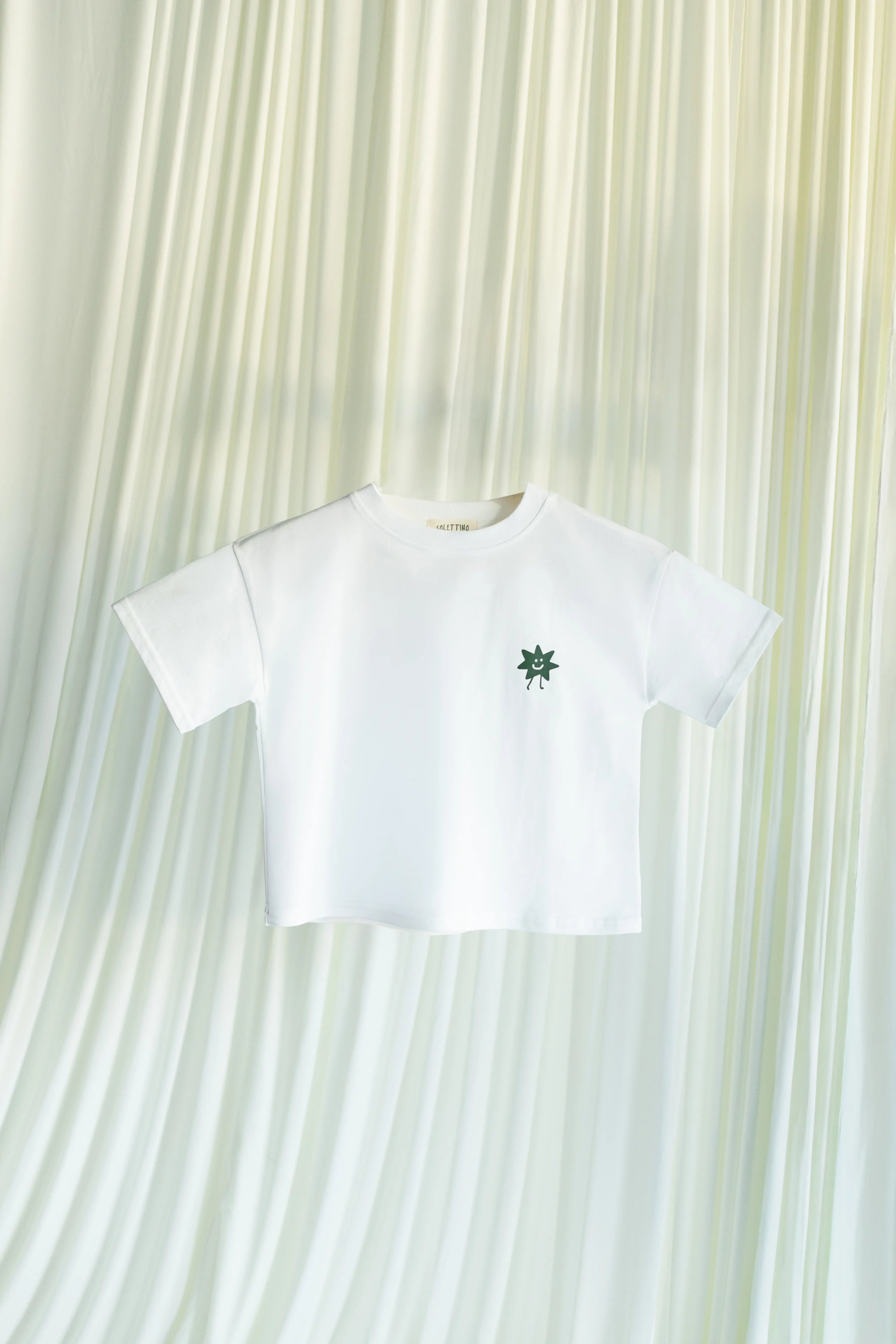 White t-shirt with Solettino Kids green logo on a white background