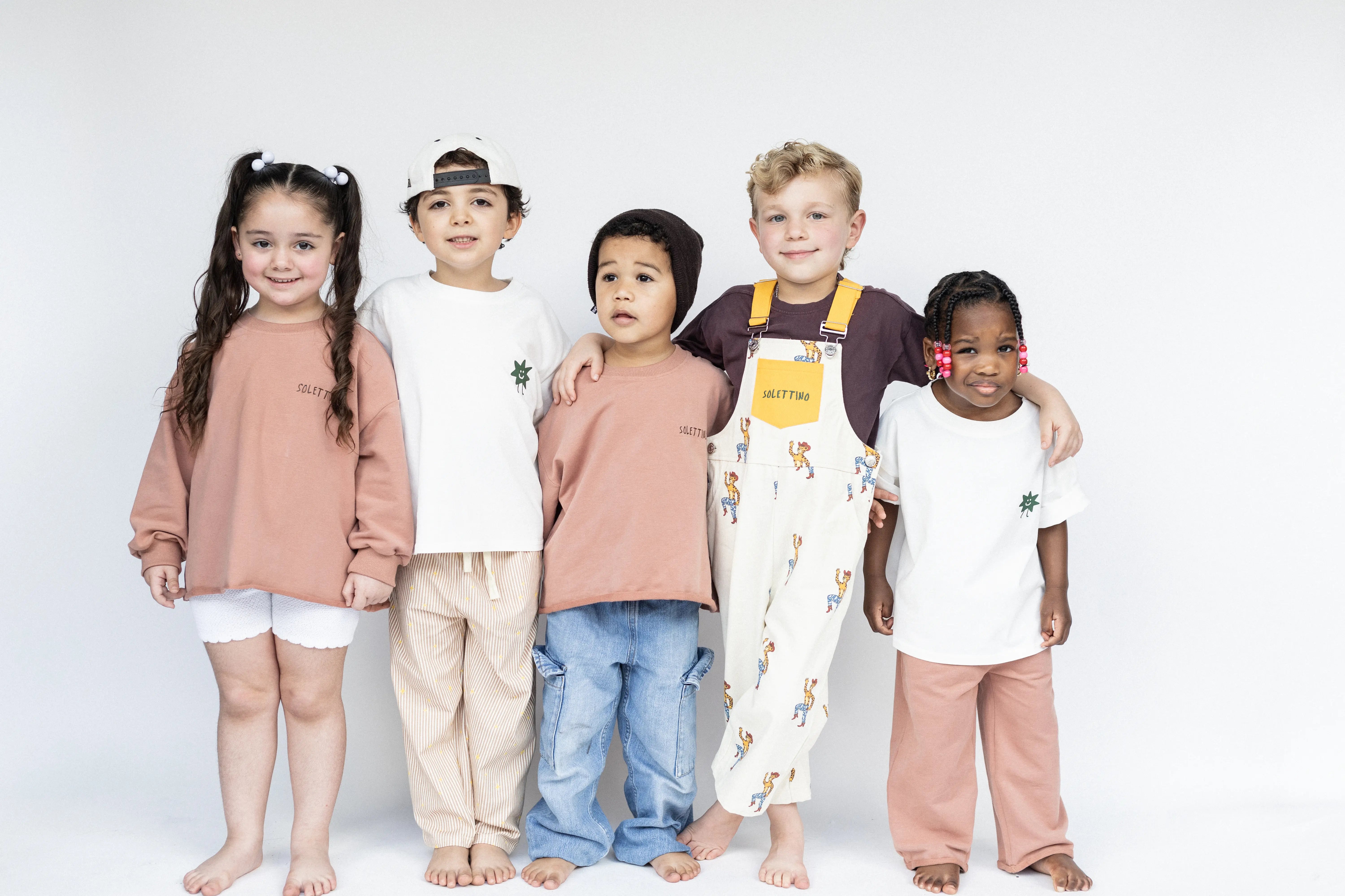 Group of children wearing a variety of outfits on a white background